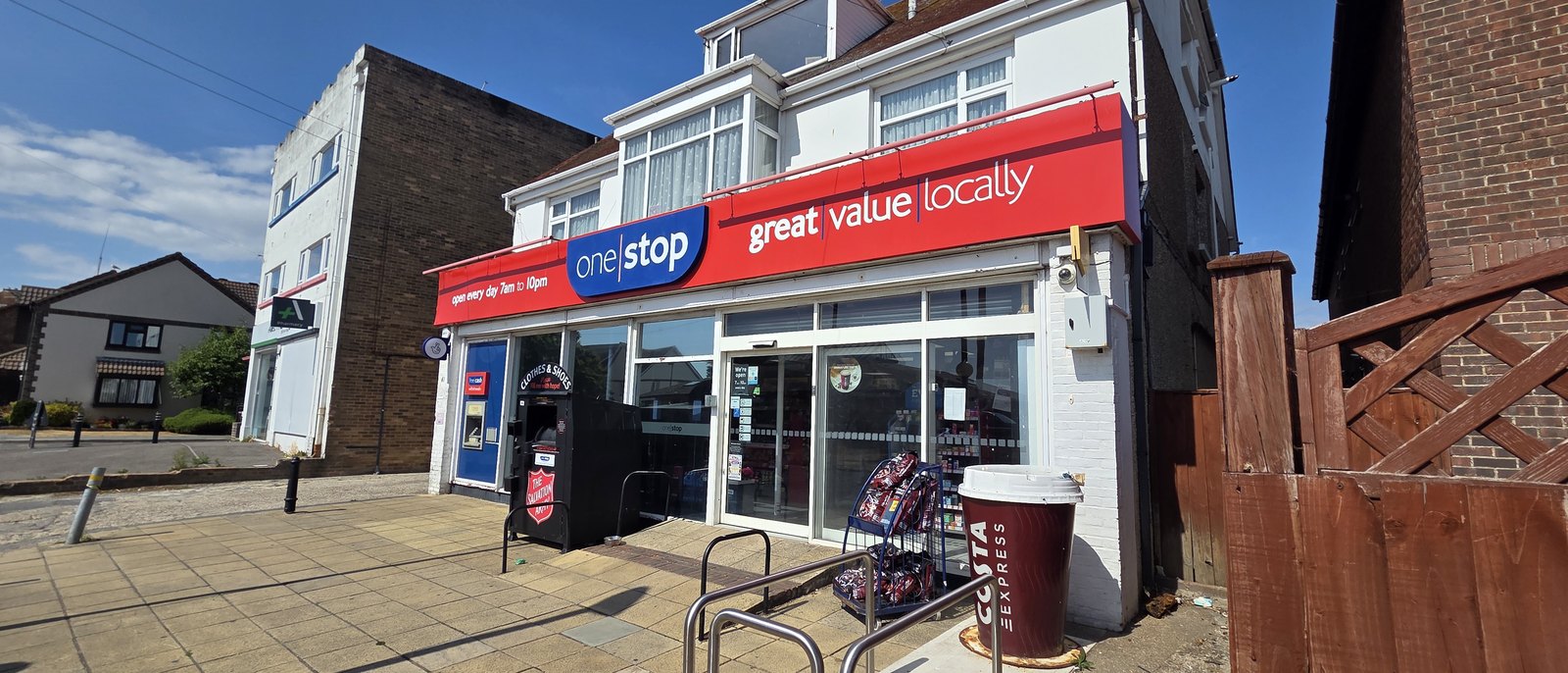 The One Stop shop on Elmer Road, a red fascia reading great value locally and open every day 7am to 10pm, with a cash machine and a Salvation Army clothing bank outside