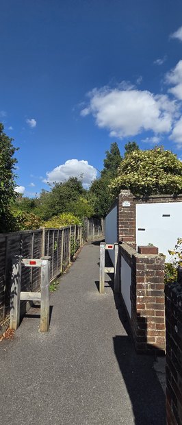 The twitten between West Close and Merry End, with timber chicane barriers across the path